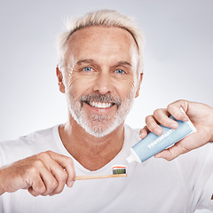 Image showing Toothbrush, face and senior man with toothpaste in studio on a gray background. Portrait, cleaning and elderly male model holding product for brushing teeth, dental wellness and healthy gum hygiene.