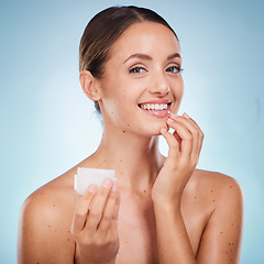 Image showing Portrait, beauty and product with a model woman holding a container in studio on a blue background to promote skincare. Face, wellness or luxury and an attractive female with cream to apply on skin