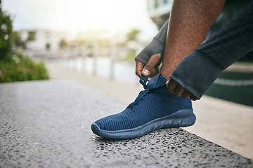 Image showing Hands, fitness and black man tie shoes in city and getting ready for running, workout or exercise. Sports, wellness and male runner tying sneaker lace and preparing for training on street outdoors.