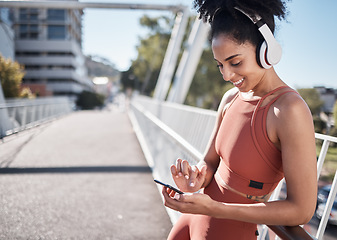 Image showing Fitness, headphones and black woman with phone in city for social media or texting. Sports, exercise and happy female on break streaming music, radio or podcast on 5g mobile smartphone after training