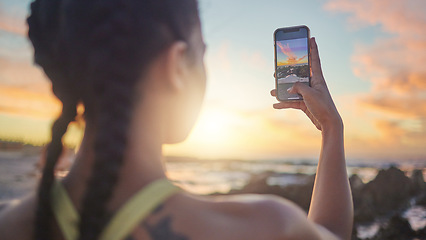 Image showing Beach, phone and woman taking photo of sunset for social media during evening workout in Bali. Nature, ocean and fitness influencer with picture of sun in blue sky on smartphone screen in Indonesia.