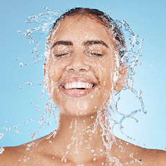 Image showing Laughing woman, washing face or water splash skincare in relax healthcare wellness or grooming hygiene cleaning on blue background studio. Smile, beauty model or wet water drops in facial dermatology