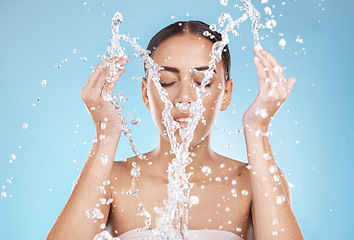 Image showing Woman, skincare or washing face with water splash on blue background studio for healthcare wellness, hygiene maintenance or bathroom grooming. Beauty model, hands or facial cleaning with water drops