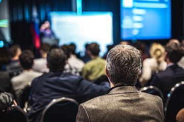 Image showing Speaker giving a talk in conference hall at business event. Rear view of unrecognizable people in audience at the conference hall. Business and entrepreneurship concept.