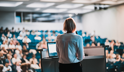 Image showing Female speaker giving a talk on corporate business conference. Unrecognizable people in audience at conference hall. Business and Entrepreneurship event.