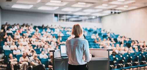 Image showing Female speaker giving a talk on corporate business conference. Unrecognizable people in audience at conference hall. Business and Entrepreneurship event.