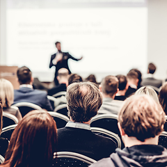 Image showing Speaker giving a talk in conference hall at business event. Rear view of unrecognizable people in audience at the conference hall. Business and entrepreneurship concept.