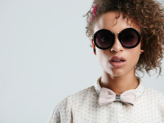 Image showing African woman, fashion sunglasses and studio headshot for makeup, beauty or curly hair afro by gray background. Black woman, dark glasses and edgy portrait for bow tie, trendy aesthetic and confident