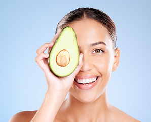 Image showing Woman, studio portrait and avocado skincare with smile, health or wellness by blue background. Model, fruit and face with natural cosmetic beauty, glow or healthy aesthetic with self care by backdrop