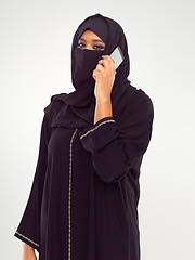 Image showing Muslim woman on a phone call in studio global, international communication of culture and design. Islam, arabic and traditional model talking on smartphone for networking isolated on white background