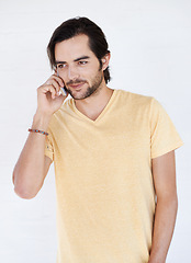 Image showing Man, phone and phone call in studio, happy and relax while standing against white background space. Young, handsome and casual guy enjoying call, conversation and speaking while chilling and isolated