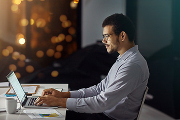 Image showing Businessman, laptop and typing with smile for research, analysis or web design on desk at the office. Employee man sitting and working on computer late at night in dedication to meet project deadline