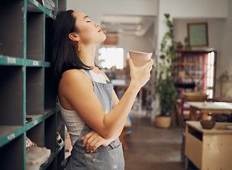 Image showing Pottery, coffee and relax with an asian woman taking a break from design in her studio or workshop. Creative, rest and small business with a female artist standing eyes closed in her ceramics startup