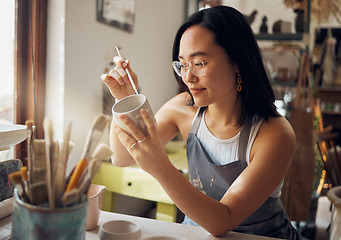Image showing Asian woman, clay studio and painting design of ceramic sculpture product, creative manufacturing and workshop. Painter, pottery artist and brush mug, pattern process and production in small business