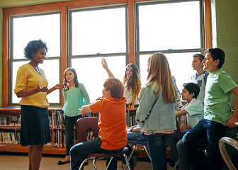 Image showing Learning, education and student with questions for teacher in middle school classroom. Library, scholarship group and male learner raising hand to answer question, studying or help with black woman.