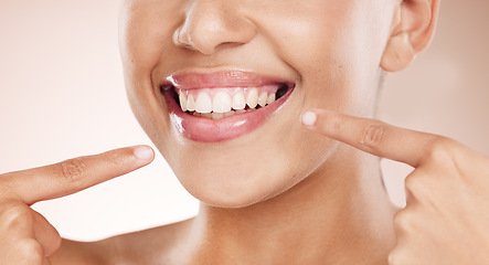 Image showing Smile, mouth and woman pointing to teeth on studio background for wellness, aesthetic beauty and healthy cosmetics. Closeup model showing clean dental skin, fresh breath and teeth whitening results