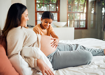 Image showing Pregnant mom and curious child on bed touching belly with excited, happy and joyful smile. Indian family and kid waiting for baby sibling and bonding together with mother in home bedroom.
