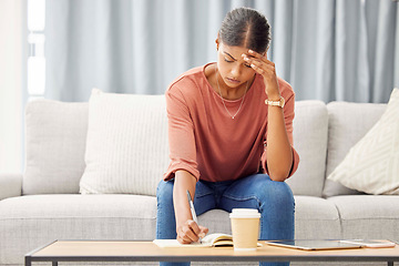 Image showing Stress, woman writing and sofa with headache, mental health and debt pressure. Latino female, girl and make notes in book, journal and budget with financial crisis, depression and anxiety in lounge