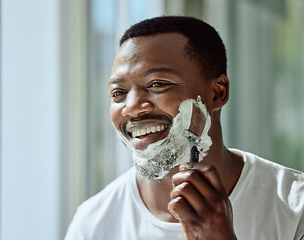 Image showing Face, shaving and razor with a black man grooming in the bathroom mirror of his home for beauty or skincare. Beard, shave and blade with a handsome male in the morning for his hair removal routine