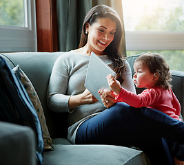 Image showing Mother, tablet and baby on living room sofa for entertainment, bonding or time together at home. Happy mom with cute little daughter, child or kid relaxing on the couch with touchscreen at the house