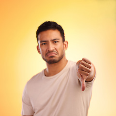 Image showing Man, thumbs down and studio portrait with sad, depressed face and frustrated by yellow studio background. Young model, depression or hand sign for emotion, communication and mental health problem