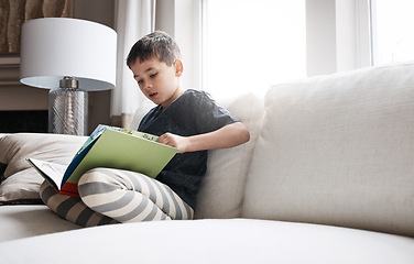 Image showing Child, boy or reading book for education, learning and relax studying on house living room or family home sofa. Kid, storytelling or fantasy fairytale novel for hobby activity or creative inspiration