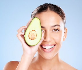 Image showing Woman, studio portrait and avocado skincare with smile, health or wellness by blue background. Model, fruit and face with natural cosmetic beauty, glow or healthy aesthetic with self care by backdrop