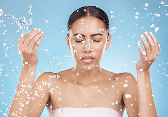 Image showing Woman skincare, washing face or water splash on blue background studio for dermatology wellness, healthcare hygiene maintenance or grooming. Beauty model, hands or wet water drops for facial cleaning