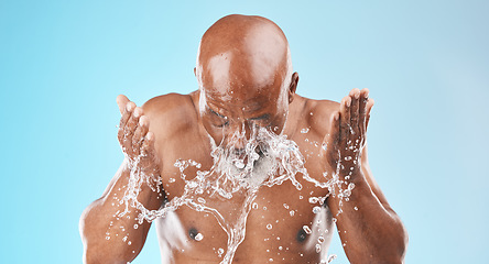 Image showing Water splash, black man and facial skincare on blue background for shower, wellness and clean body care with personal hygiene. Male beauty, studio model and washing face with water drops in bathroom