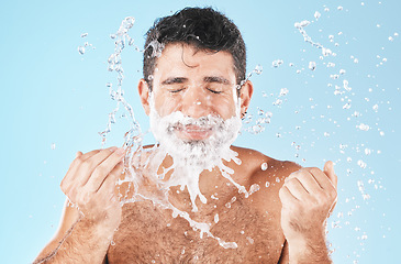 Image showing Man, shave and water splash for beauty in studio with wellness, health or self care by blue background. Model, cream and water with hands for healthy facial, self love or cosmetics by studio backdrop