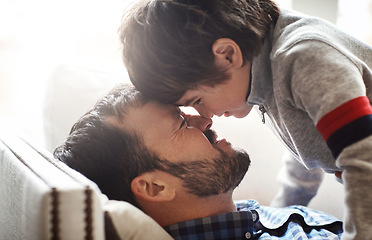 Image showing Father, child and forehead playing on sofa in living room for quality bonding time together at home. Happy dad enjoying holiday, break or play with son relaxing with smile for love and care on couch