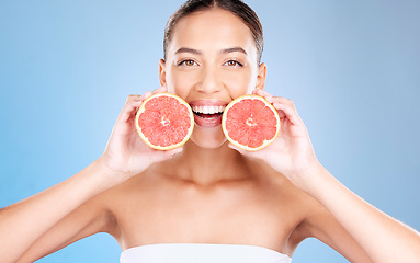 Image showing Woman, studio portrait and grapefruit for skincare, natural cosmetic or health by blue background. Model, fruit and smile for nutrition, vitamin c or self care beauty for aesthetic by studio backdrop