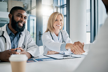 Image showing Handshake, partnership or happy doctors in a meeting after successful medical surgery or reaching healthcare goals. Teamwork, woman or black man smiles shaking hands with a worker in hospital office