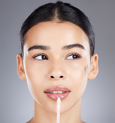 Image showing Woman, lip gloss and face makeup isolated on a grey background for beauty, glow or cosmetics. Beautiful female model applying glowing or glossy lipstick to lips, mouth or skin for cosmetic facial