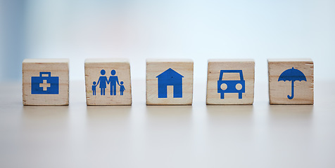 Image showing Medical, house and life insurance on blocks background for family clinic, safety and healthcare icon or sign. Future goals, risk management and car or home cover with umbrella on wood for services