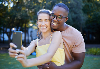 Image showing Selfie, phone and interracial couple hug in park enjoying weekend, summer holiday and quality time together. Nature, dating and happy man and woman take picture on smartphone relax, calm and freedom