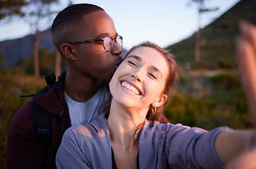 Image showing Interracial couple, kiss and smile for selfie, travel or love for adventure, journey or hiking together in nature. Happy man kissing woman smiling in happiness for photo moments, trip or traveling