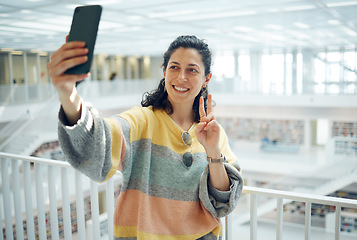 Image showing Selfie, phone and peace with a woman in a library for research while posing for a social media photograph. Mobile, communication and hand gesture with a female student taking a picture in a bookstore
