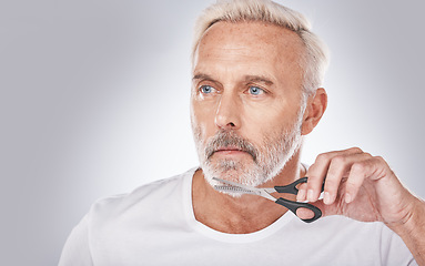 Image showing Facial hair, cutting and man with scissors for grooming, shaping and routine treatment on a studio background. Barber, cleaning and face of a senior model trimming beard during morning clean