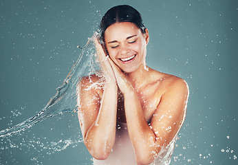 Image showing Water, wellness and cleaning with a woman in studio on a blue background for hygiene or hydration in the shower. Spa, splash and beauty with an attractive young female washing in the bathroom