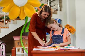 Image showing Creative kids during an art class in a daycare center or elementary school classroom drawing with female teacher.