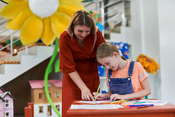 Image showing Creative kids during an art class in a daycare center or elementary school classroom drawing with female teacher.