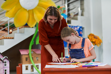 Image showing Creative kids during an art class in a daycare center or elementary school classroom drawing with female teacher.