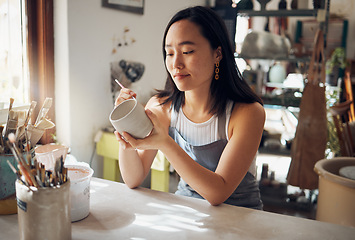 Image showing Pottery, art and sculpture with a japanese woman in a studio for design or a creative hobby as an artisan. Manufacturing, pattern or artist with a female potter sitting in her workshop as a sculptor