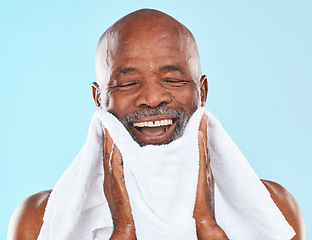 Image showing Black man, studio and towel for shave, smile and wellness for self care, hygiene and beard by blue background. Senior man, happy and cloth for skincare, wellness and grooming routine by backdrop