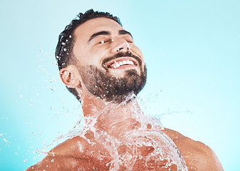 Image showing Water, splash and skincare with face of man for shower, self care and natural cosmetics. Luxury, hydration and refreshing with model for dermatology, wellness and cleaning in blue background studio