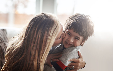 Image showing Family, children and love with a mother kissing her son in the living room of their home while bonding together. Kids, kiss and smile with a woman hugging her boy child on the cheek in a house