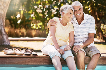 Image showing Senior couple, hug and swimming pool for summer vacation, love or relax spending quality bonding time together. Happy elderly man holding woman relaxing with feet in water by the poolside outside