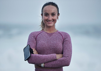 Image showing Portrait, runner and woman with arm band, music earphones and motivation for cardio fitness in Sweden. Happy young athlete, arms crossed and training for healthy lifestyle, energy and sports wellness