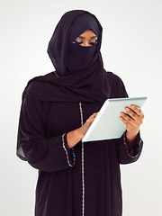 Image showing Woman, tablet and muslim typing with hijab for online islamic research against grey studio background. Female isolated standing holding touchscreen with scarf reading news on islam, arabic or culture